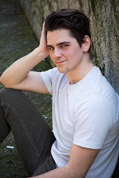 istock Attractive young man sitting on the ground against rock 518570047