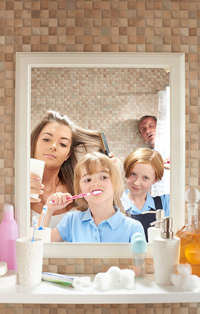 Bathroom morning privacy Three daughters of mixed ages fight for mirror space at the start of the day , much to there annoyance of father who is trying to have a shower in peace . He looks from the shower curtain annoyed at the lack of privacy . vanity mirror photos stock pictures, royalty-free photos & images