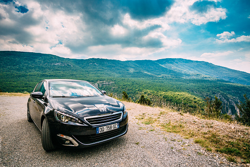 Verdon, France - June 29, 2015: Black colour Peugeot 308 5-door car on background of French mountain nature landscape. The Peugeot 308 is a small family car produced by French car manufacturer Peugeot