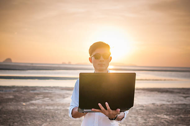 istock Business man working with laptop and smartphone beach background 518587070