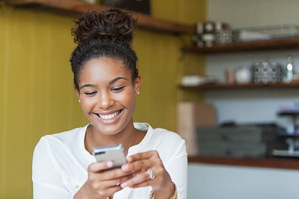 Young woman texting Happy young woman texting. black woman hair bun stock pictures, royalty-free photos & images