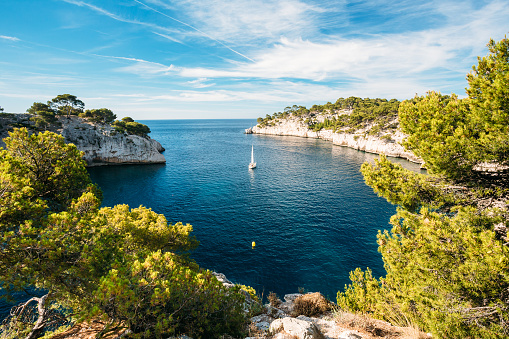Beautiful nature of Calanques on the azure coast of France. Calanques - a deep bay surrounded by high cliffs. Boat leaves from bay to open sea.