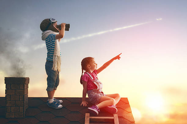 Two little children Two little children playing on the roof of the house and looking at the sky and dreaming of becoming a pilots. dawn of new era stock pictures, royalty-free photos & images