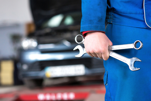 Hand of car mechanic with wrench. Auto repair garage.