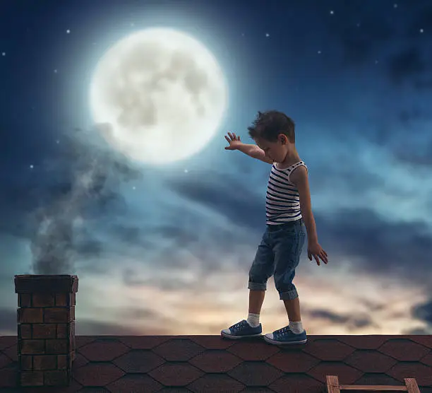 Child boy walks on the roof in the moonlight.