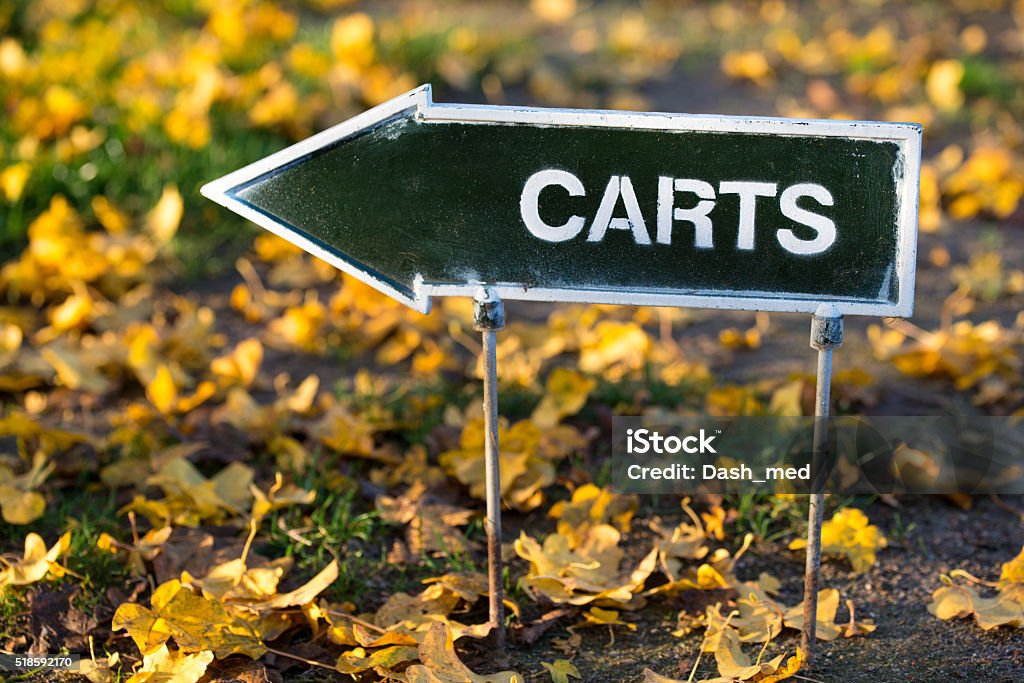 The golf carts direction sign on autumn golf field The golf carts direction sign on autumn golf field, yellow leaves on the ground. Activity Stock Photo