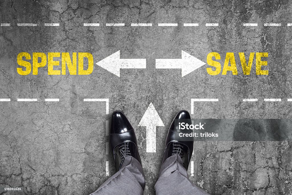 Decision at a wall - Spend or Save Low section view of a man standing by text Spend or Save with arrow sign represents the concept of shopping. Commercial Activity Stock Photo