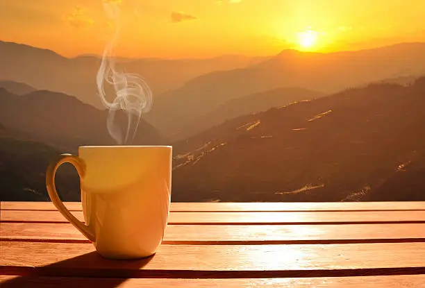 Morning cup of coffee with mountain background at sunrise