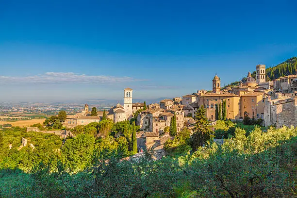 Panoramic view of the historic town of Assisi in beautiful golden morning light at sunrise in summer, Umbria, Italy.