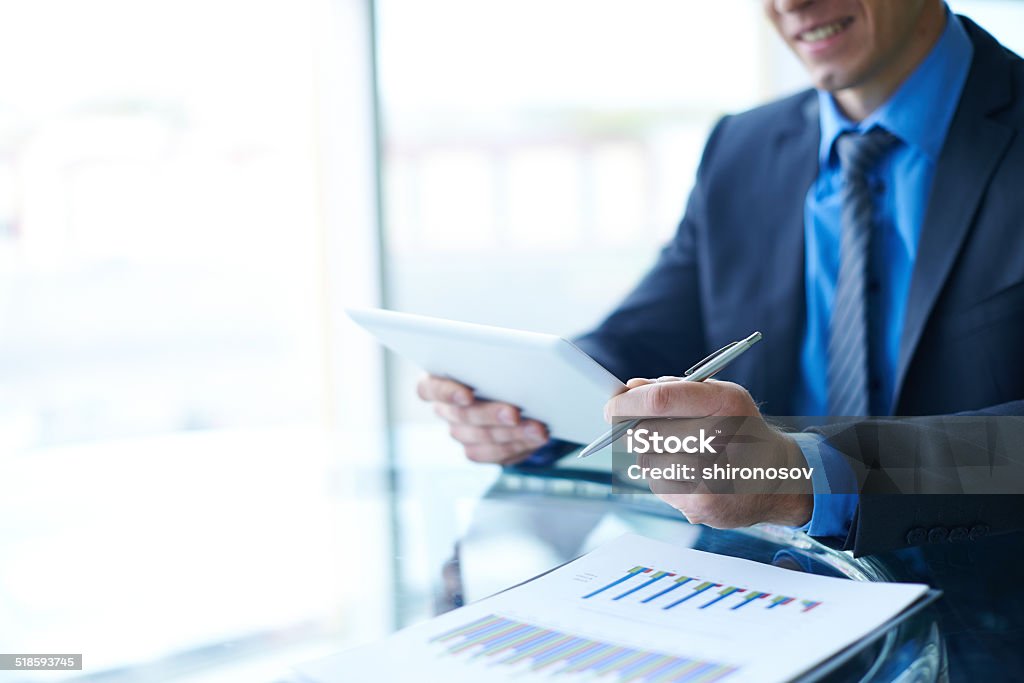 Electronic data Businessman with pen and touchpad sitting at workplace Adult Stock Photo