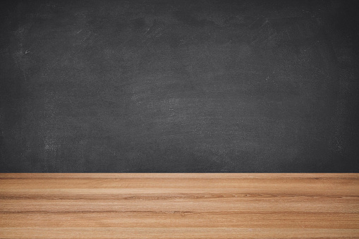 Empty school desk border against blackboard background, ideal for product display on top of the desk and with plenty copy space on the blackboard background.