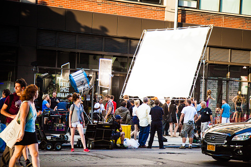 New York City, New York, United States - August 21, 2014: Cameramen and crew setting up a shoot on street in Chelsea, New York for a movie set. A lot of crowd and curious people looking at the scene.