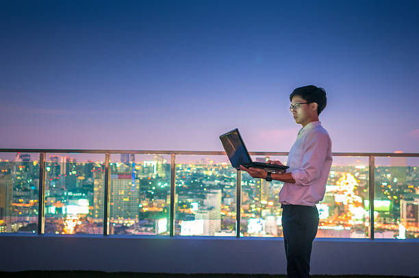 istock Businessman using a laptop on the rooftop of a skyscraper 518599322