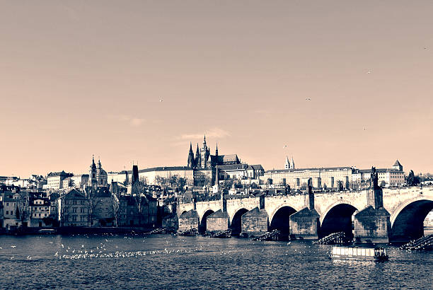 Charles' Bridge, Prague castle and Vltava river on a sunny day, in black and white. Monochrome image filtered in retro, vintage style with soft focus and red filter; nostalgic concept of travel.