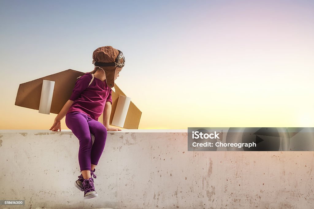 girl plays astronaut Little child girl plays astronaut. Child on the background of sunset sky. Child in an astronaut costume plays and dreams of becoming a spaceman. Child Stock Photo