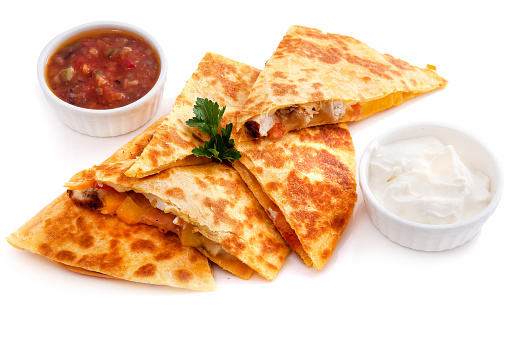 Five pieces Mexican quesadillas with cheese, two sauces and salsa isolated on white