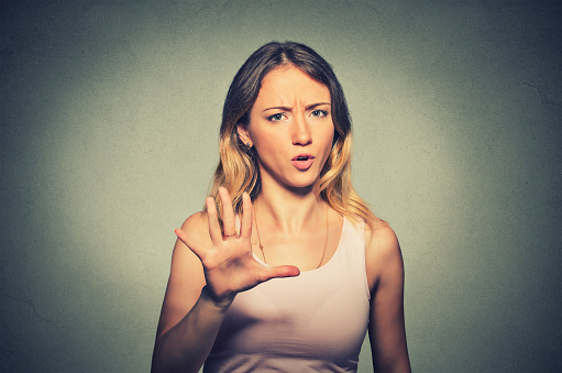 Closeup portrait of angry annoyed woman raising hand up to say no stop right there isolated on gray background. Negative human emotion facial expression