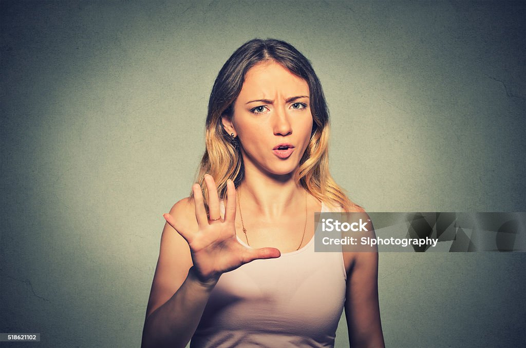 angry annoyed woman raising hand up to say no stop Closeup portrait of angry annoyed woman raising hand up to say no stop right there isolated on gray background. Negative human emotion facial expression Women Stock Photo