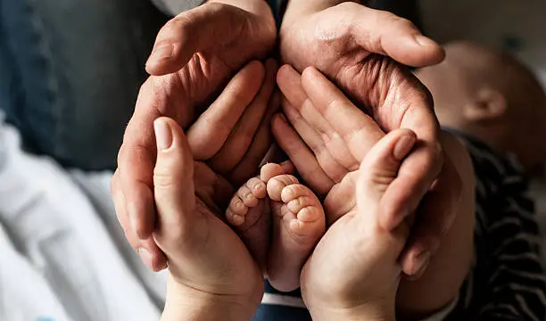 Photo of Little child foot in parents palms