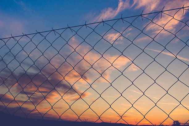 istock sunset behind chain link fence 518625578