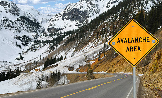 Avalanche and Sign A sign warns motorists in an area of southwest Colorado where an avalanche has recently covered the road. avalanche stock pictures, royalty-free photos & images
