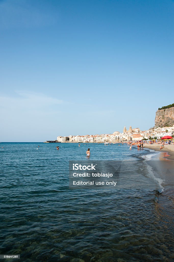 Beach in Cefalu Sicily Cefalu, Italy - September 19, 2014: People enjoying the sun at a crowded beach near the old town of Cefalu, Sicily. Beach Stock Photo