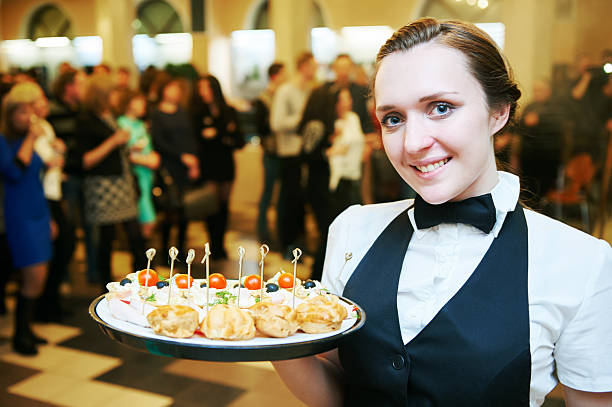 Catering service. waitress on duty Catering service. Restaurant waitress girl with food tray at event. Natural authentic shot in challenging light condition. buffet hotel people women stock pictures, royalty-free photos & images