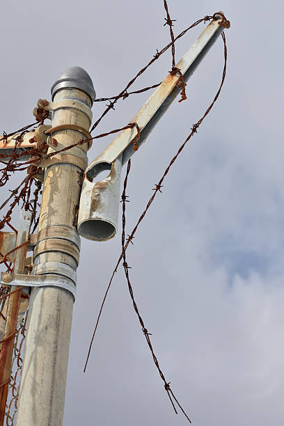 istock Barbed Wire Over Chain Link Fence Blue Cloudy Sky 518648540