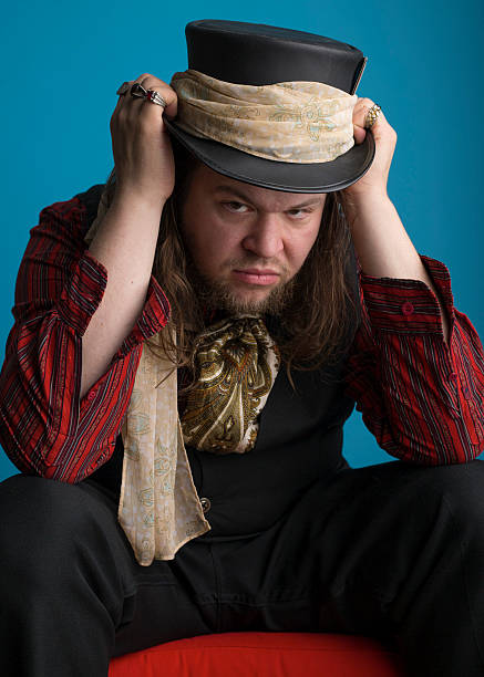 istock Man sitting and gripping top hat on his head 518654842