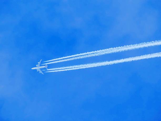 istock Airplane with chemtrails on blue sky 518654990