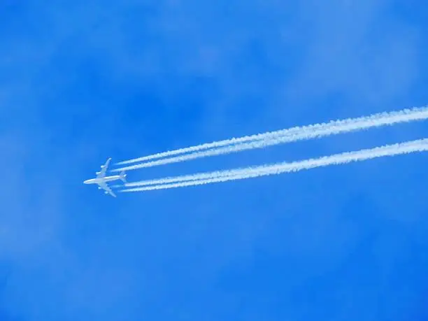 Airplane with chemtrails on blue sky 