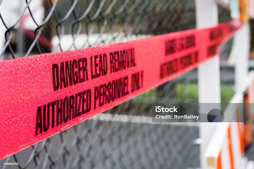 Danger Lead Removal Cordon Tape Bright red "Danger Lead Removal Authorized Personnal Only" banner running along a  chain-link fence surrounding an old bridge that the lead-based paint is being removed from.  This is the Stosel Bridge just outside the town of Carnation in the Snoqualmie Valley, Washington. Lead Paint Stock Photo