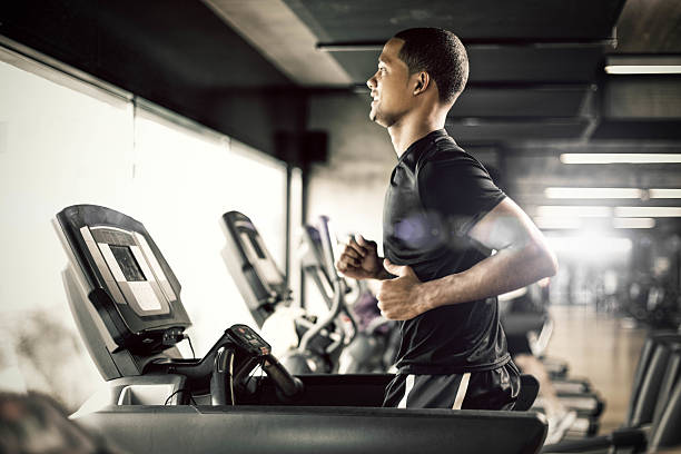 Healthy man Running on Treadmill Healthy young man in GYM running on treadmill treadmill stock pictures, royalty-free photos & images