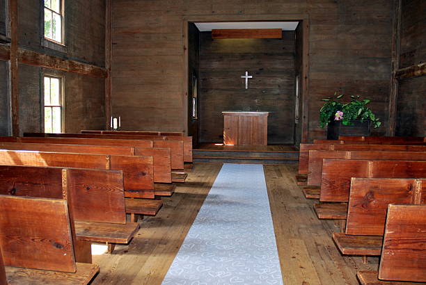 istock Old church interior with pews and a cross on wall 518657483