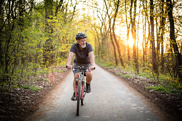 Senior man on his mountain bike outdoors Senior man on his mountain bike outdoors in forest on a lovely summer day, staying active mountain bike photos stock pictures, royalty-free photos & images