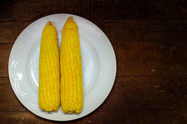 istock 2 fresh corn on dish and the wood table. 518678268