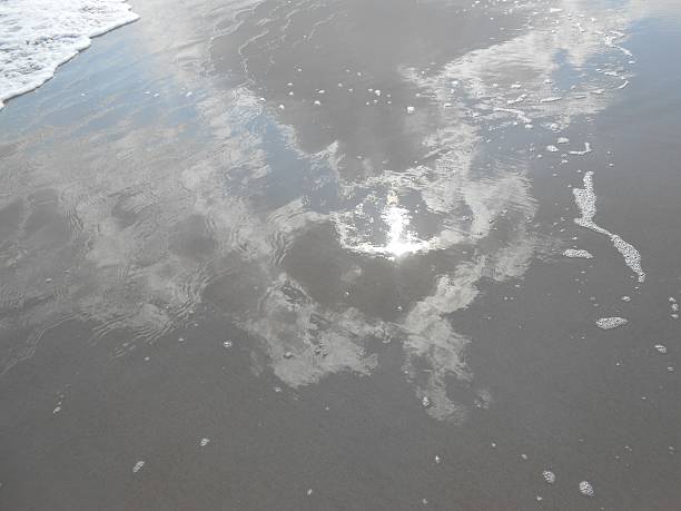 istock Clouds and Sun Reflecting in Wet Sand on Ocean Beach. 518680068