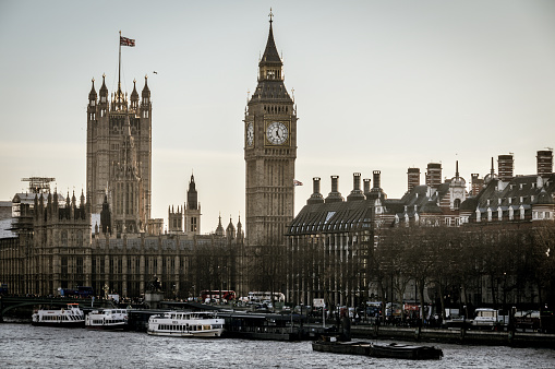 London, UK - March 15, 2016: London riverfront featuring Big Ben, Houses of Parliament, and numerous boats. Photo taken during the late afternoon.