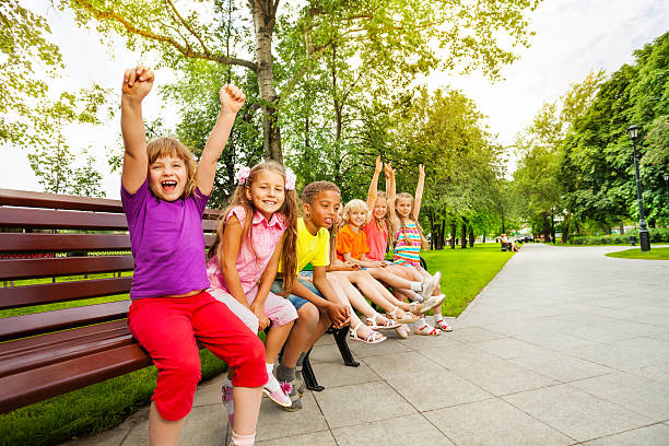 istock Kids in row on bench with some mates excited 518680767