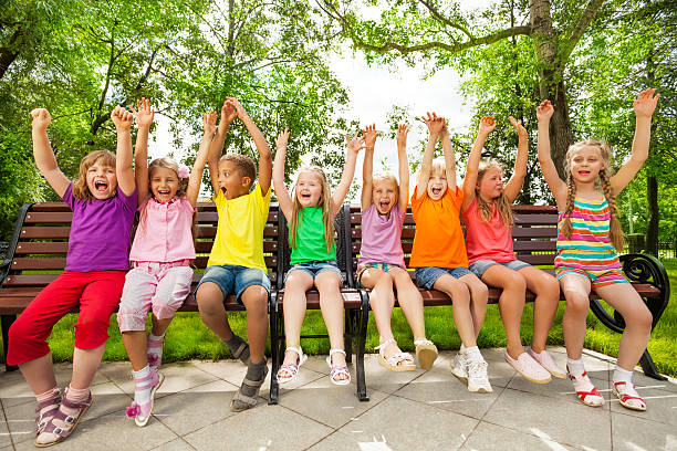 istock Funny group of kids on bench with arms up 518680837