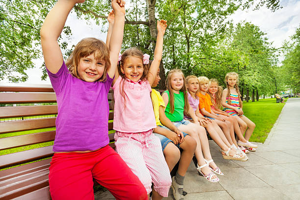 istock Smiling children sit in row on the bench 518680939