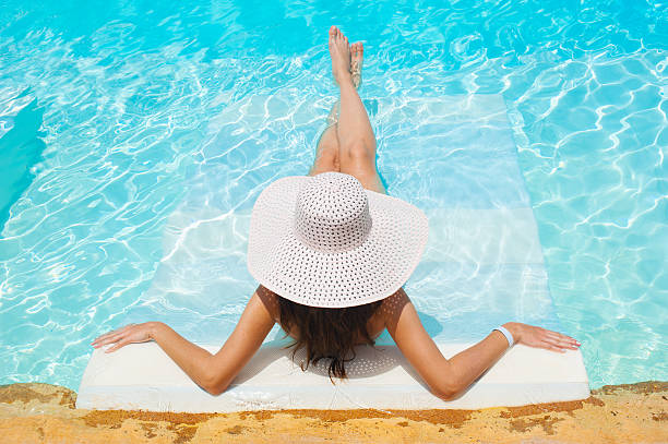 istock beautiful woman white hat and bikini lying in a pool 518684530