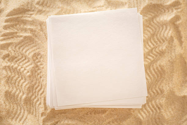 istock Blank sheets of paper on sand 518686606