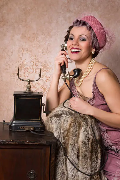Stunning vintage 1920s woman talking on an antique telephone