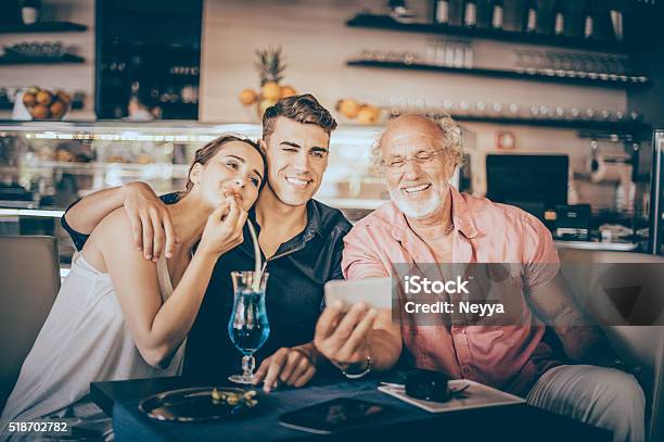 Senior Man Using Digital Tablet With Teenage Couple Stock Photo - Download Image Now