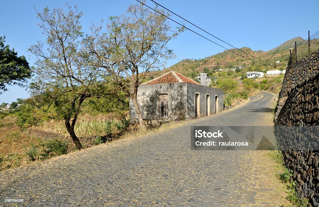 Red tiled roof home by the road Antique concrete home with red tiled roof by a cobblestone road leading to the mountain side town of Mira Mira in Fogo, Cabo Verde Cape Verde Stock Photo