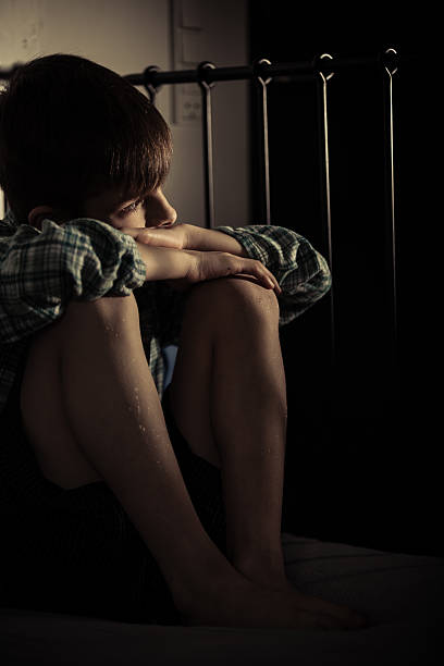 istock Lonely Boy Sitting on his Bed Inside his Room 518707178