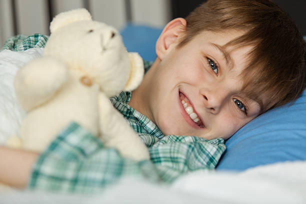 istock Happy Boy with his Teddy Bear Lying on his Bed 518707216