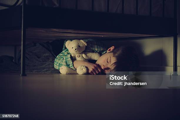 Scared Boy Sleeping Under His Bed With Teddy Bear Stock Photo - Download Image Now - Child, Shock, Hiding