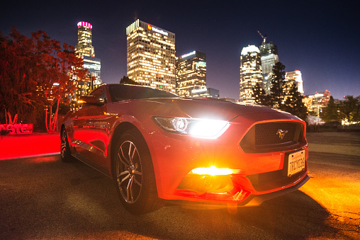 Los Angeles, California, USA - March 22, 2016: Front view of a red Ford Mustang GT car parked on the street against the Los Angeles city downtown. Ford Mustang is a sport muscle car made in US by Ford. Image taken in the night with the skyline in the background